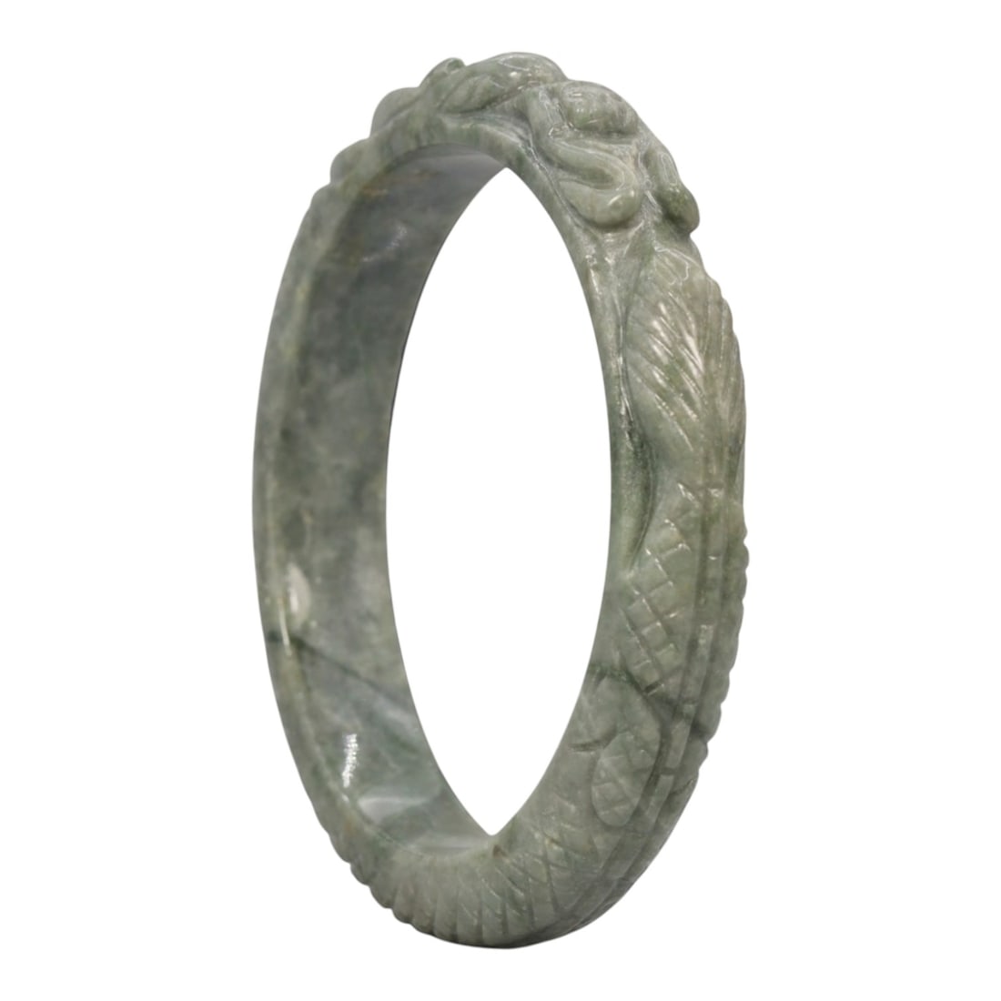 A Chinese Carved Jadeite Jade Bangle Bracelet, 20th Century, 25ZL: A fine jadeite bangle of circular form, masterfully carved in relief with a continuous band of a sinuous dragon coiling around its circumference. The stone exhibits a translucent pale green base, with
