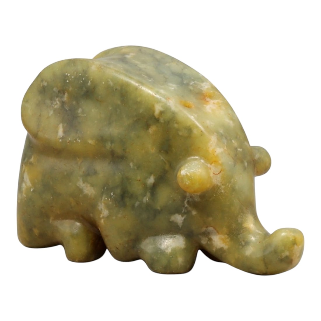 A Chinese Jade Elephant Effigy, 20th Century, 45YC: The figure is carved from jade of mottled green and pale celadon tones, with scattered lighter inclusions and areas of natural translucency. It is worked in the round as a compact elephant shown in a 