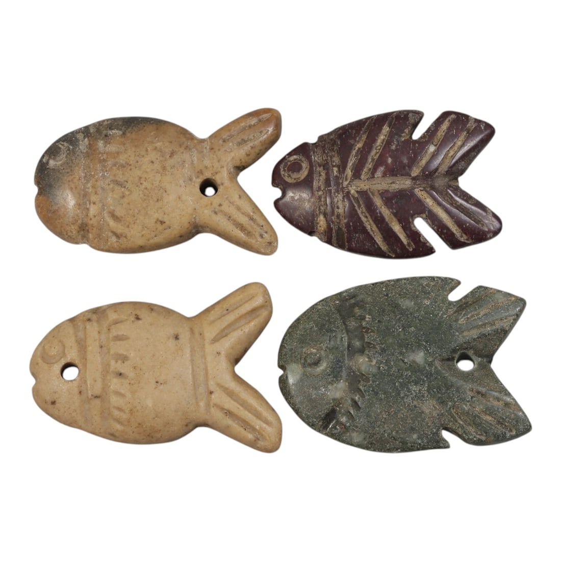 Lot of 4 Ancient Coptic Egyptian Stone Fish Amulets, Circa Roman to Coptic Era, 38AE: The group comprises four carved stone fish amulets, each rendered in stylized form with incised details defining the eyes, fins, and body segments. The pieces are worked in varied stone tones: light b