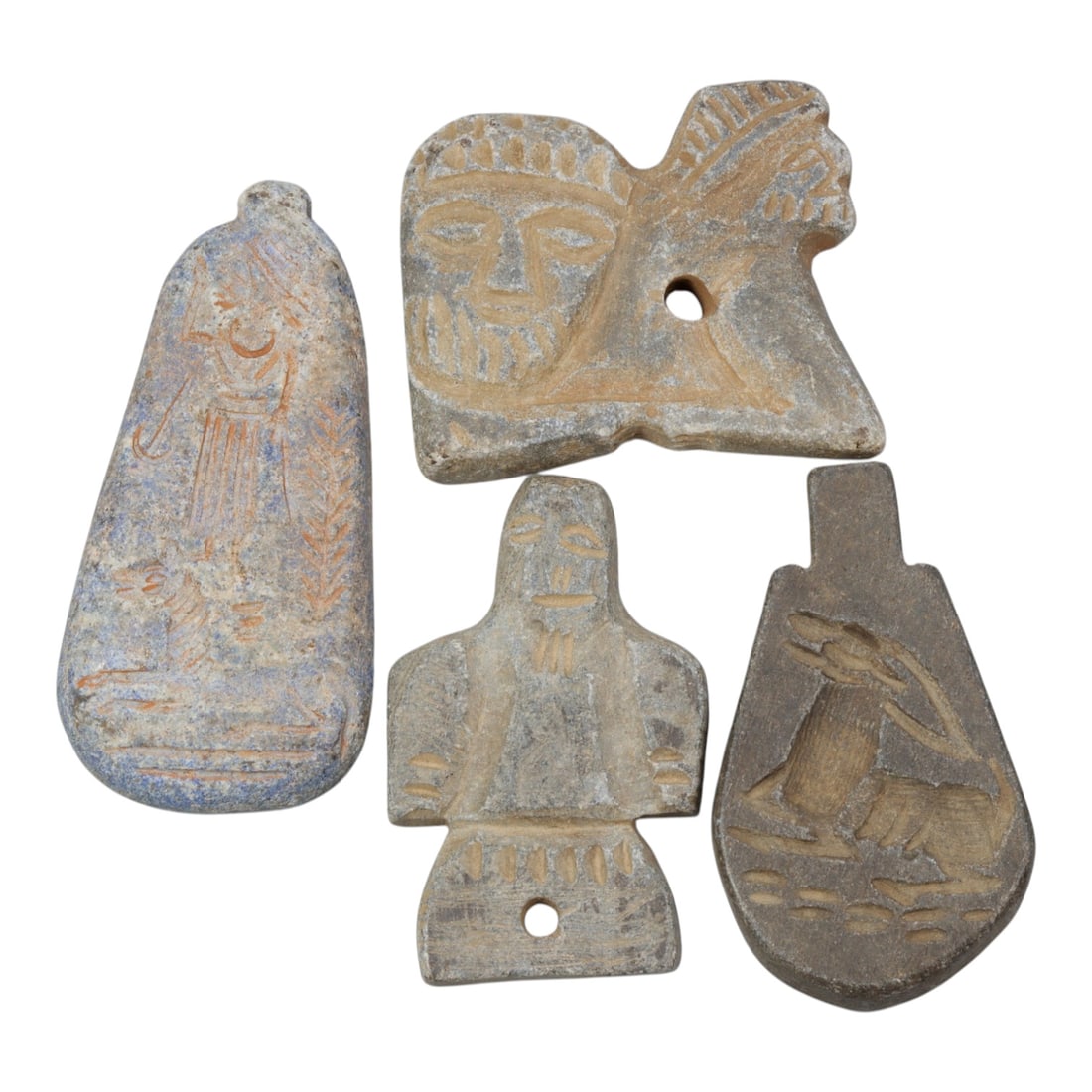Lot of 4 Ancient Near Eastern Stone Amulets, 89WM: A collection of four ancient stone amulets, carved from varied materials including light grey and blue-tinged stone. The set includes: a teardrop-shaped pendant engraved with a standing figure and pla