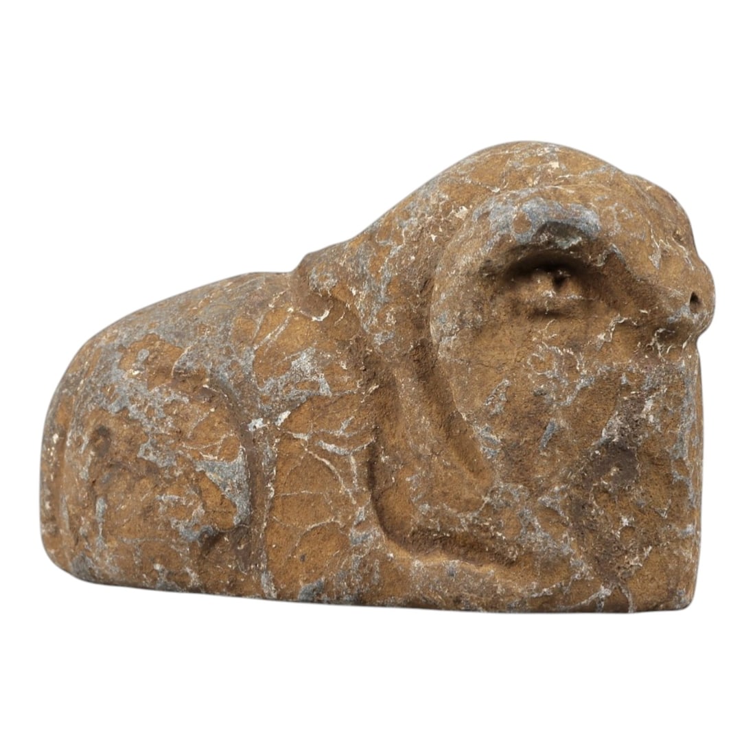 Ancient Stone Ram Effigy - Near Eastern Zoomorphic Figurine, 97FX: Carved from a weathered, veined stone, this effigy depicts a recumbent ram in a compact, stylized form. Relief details define the curled horns, snout, and rounded body, emphasizing the animal's robust