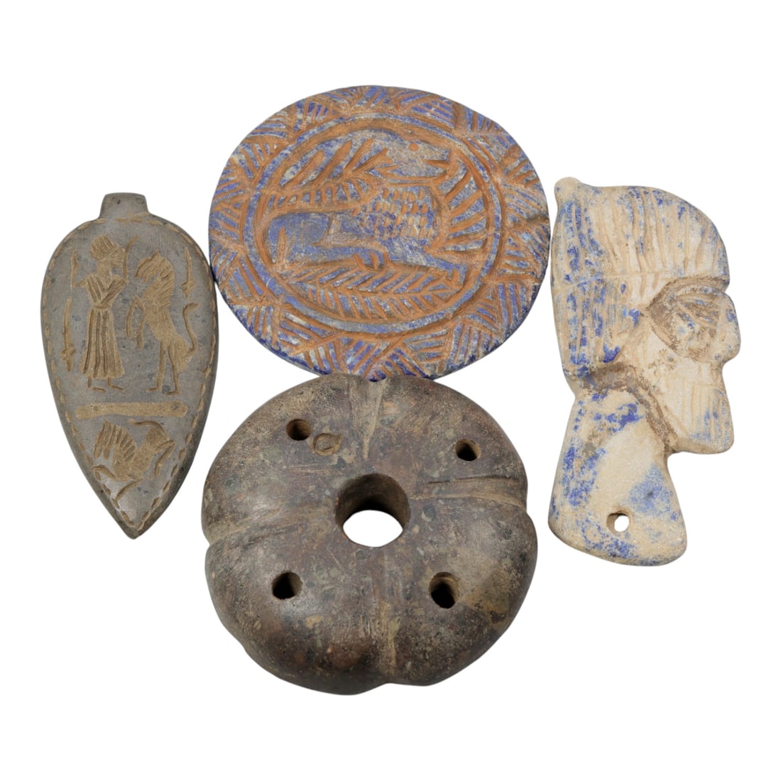 Lot of 4 Ancient Near Eastern Stone Amulets Relics, 76WP: A collection of four ancient stone relics, carved from varied materials including grey stone, lapis lazuli, and dark brown stone. The set includes: a leaf-shaped pendant engraved with human and animal