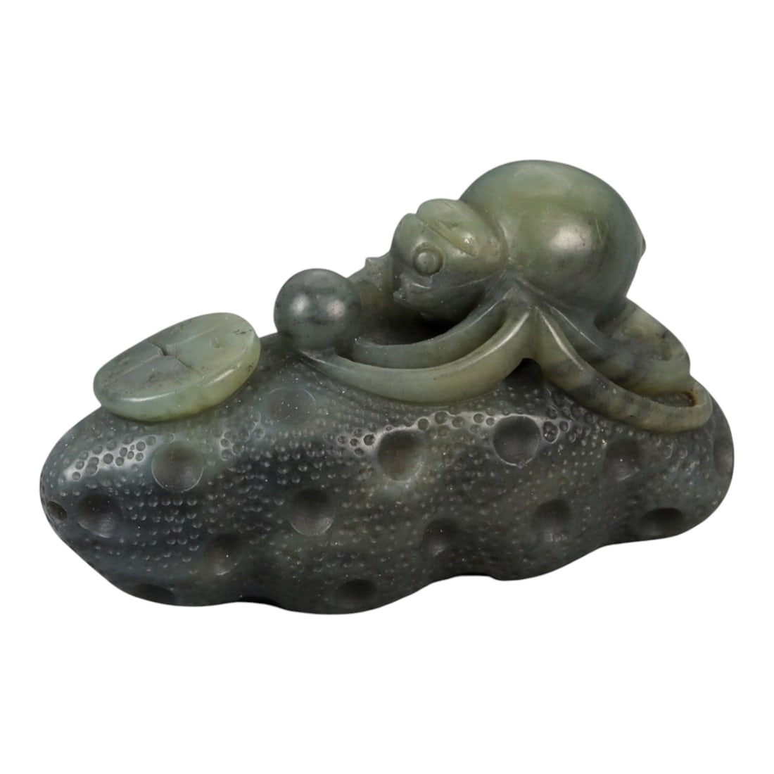 A Chinese Nephrite Jade Spider Carving, 20th Century, 77FB: Carved from dark green nephrite jade with mottled inclusions and areas of lighter translucency, the object is modeled as a spider resting upon a textured ground. The spider is carved in the round, wit