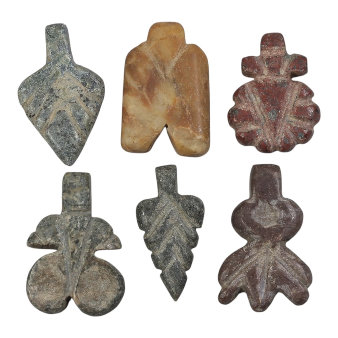 Lot of 6 Ancient Coptic Egyptian Stone Amulets, Circa Roman to Coptic Era, 84AE: The group comprises six carved stone amulets of stylized botanical and abstract forms, including leaf, floral, and geometric types. The pieces are worked in varied stone tones: grey speckled, light ye