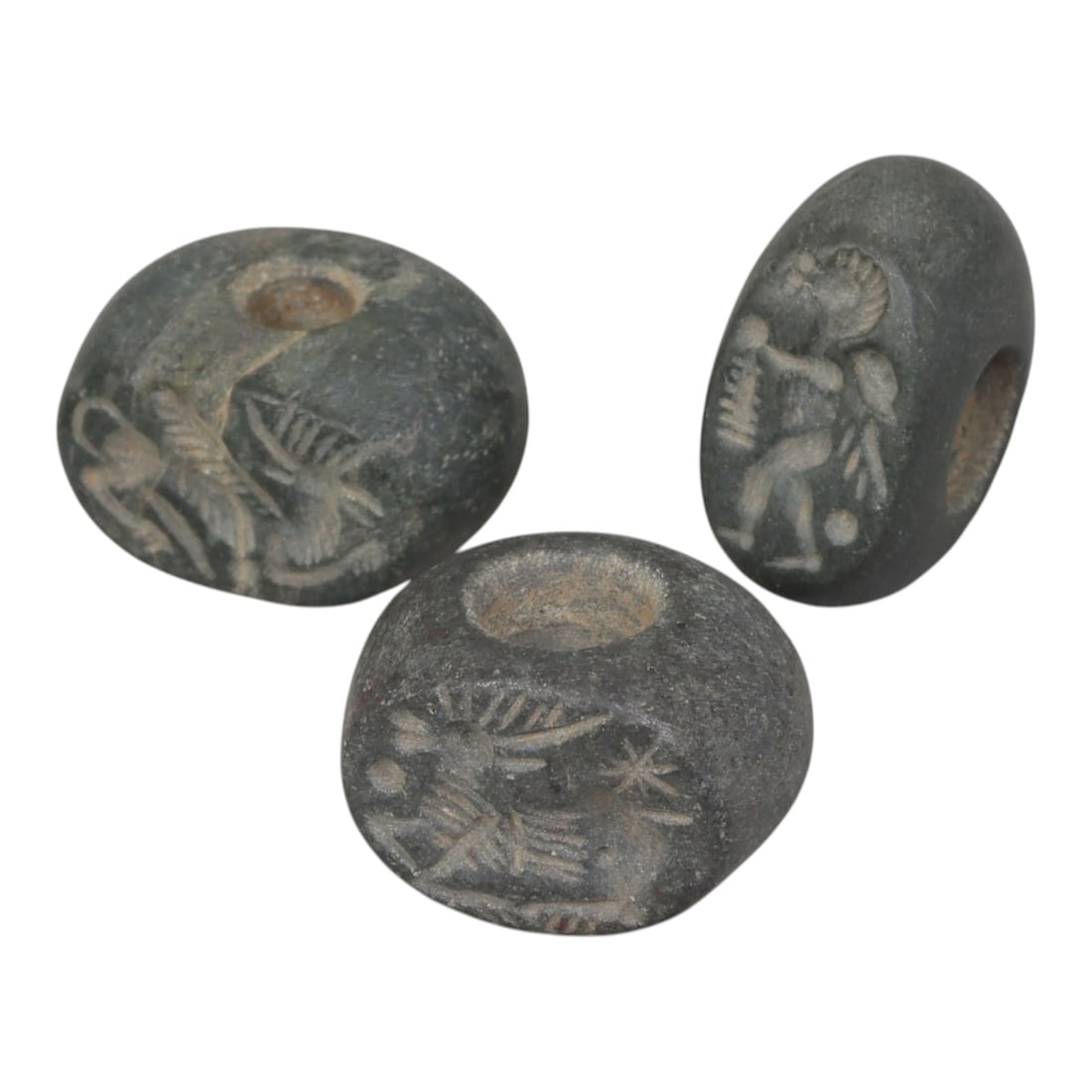 Lot of 3 Sasanian Stone Stamp Seals, Circa 3rd-7th Century CE, 4AG: Comprising three seals carved from dark grey stone with natural patina and surface wear consistent with ancient use. Each seal is of flattened disc or oval form with a central perforation for suspensi