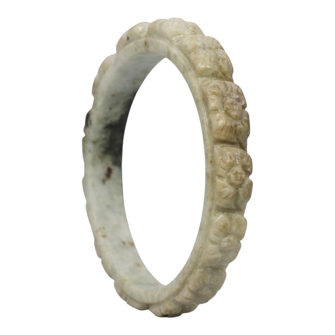 A Chinese Carved Jadeite Jade Bangle Bracelet, 20th Century, 80ZL: A fine jadeite bangle of flattened circular form, masterfully carved in relief with a continuous band of chrysanthemum blossoms. The stone exhibits a pale milky-green base, accented by subtle brownish