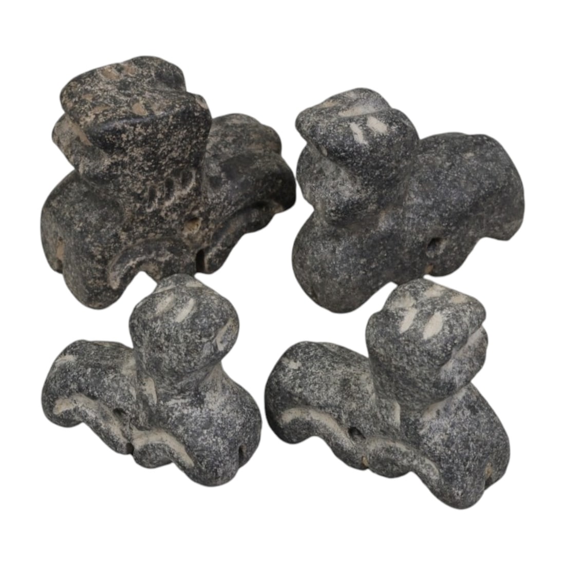 Lot of 4 Ancient Bactrian Zoomorphic Feline Stone Amulets, 47AH: A set of four ancient zoomorphic amulets, hand-carved from dark grey speckled stone, characteristic of Bactrian (Central Asian) craftsmanship. Each piece depicts a stylized feline figure with a compac