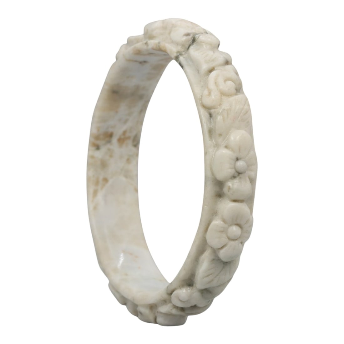A Chinese Carved Jadeite Jade Bangle Bracelet, 20th Century, 75ZL: A fine jadeite bangle of flattened circular form, masterfully carved in relief with a continuous band of floral blossoms and scrolling foliate motifs. The stone exhibits a creamy white base, heavily a