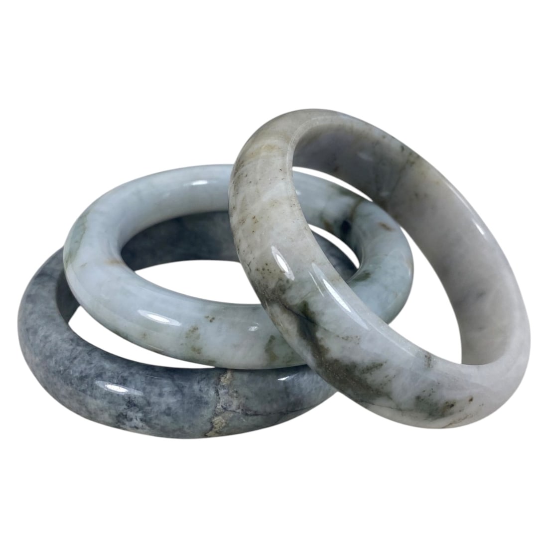 Lot of 3 Chinese Polished Jadeite Jade Bracelets (Bangles), 83AC: Each bracelet is a smooth, uncarved circular bangle crafted from jadeite. The pieces exhibit varied natural coloration, including pale greyish-white with green and grey inclusions, light blue-grey wit