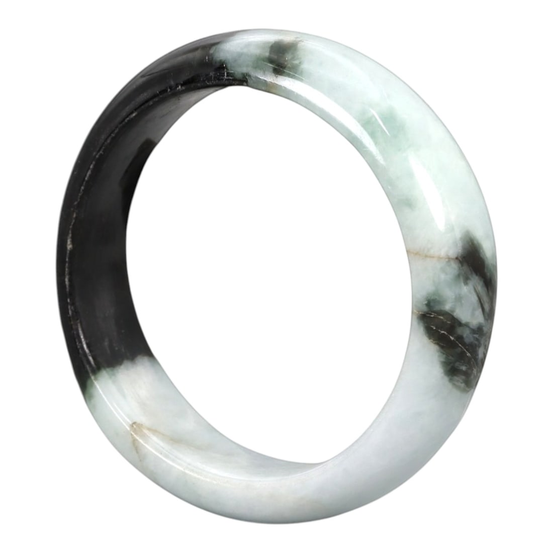 A Chinese Jadeite Jade Bangle Bracelet, 20th Century, 99ZK: Carved from jadeite jade with a striking bi-color composition of opaque pale white and translucent deep blackish-green, the bangle is formed as a solid circular band with a flattened rounded cross-sec