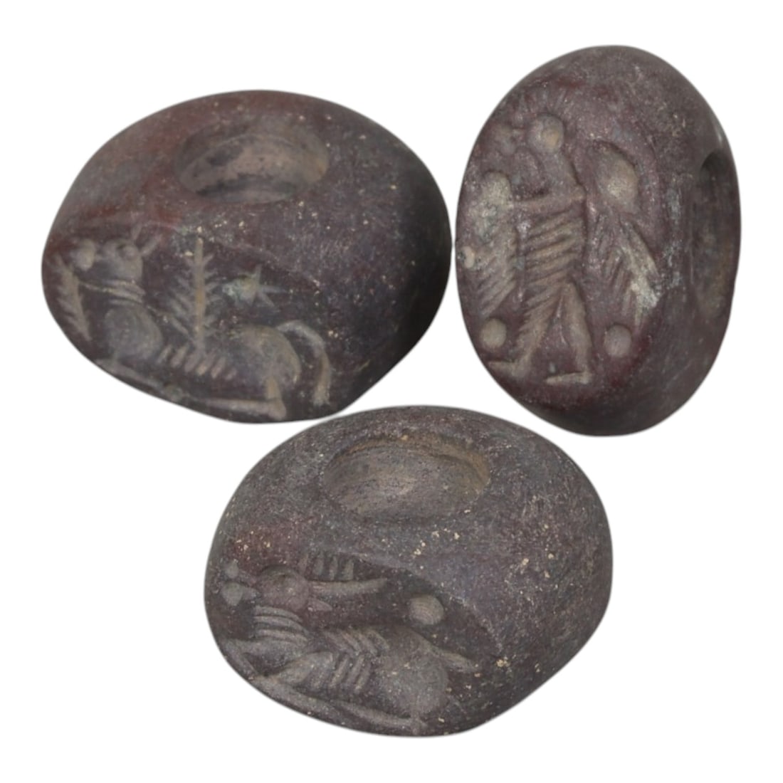 Lot of 3 Sasanian Stone Stamp Seals, Circa 3rd-7th Century CE, 10AG: Comprising three seals carved from dark reddish-brown stone with natural patina and surface wear consistent with age. Each seal is of rounded disc or oval form with a central perforation for suspensio