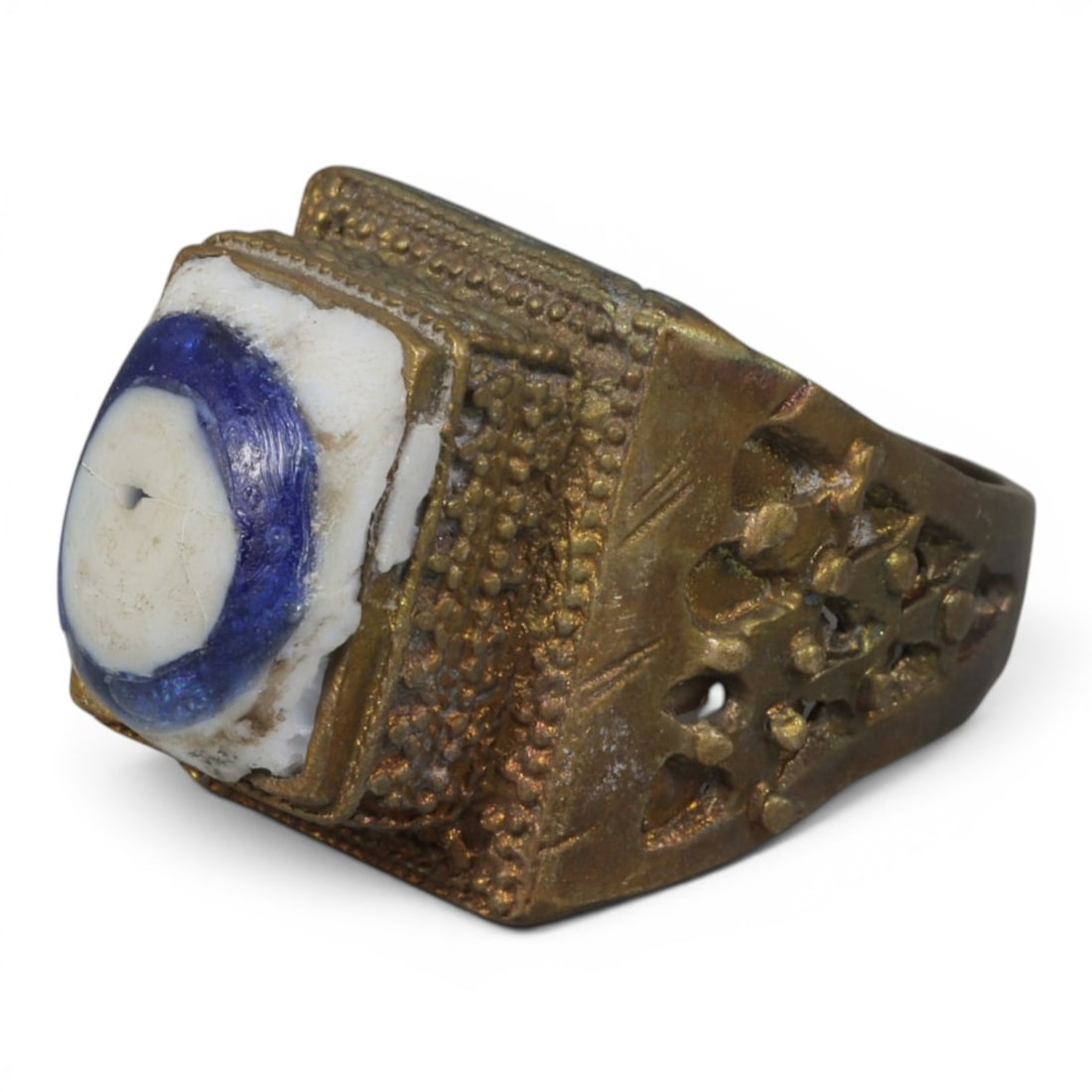 Antique Qajar Dynasty Gilt Evil Eye Ring, US Size 10, 14AJ: A gilt-metal ring of the Qajar period, US ring size 10, featuring a rectangular bezel set with a blue-and-white evil-eye glass inlay. The ring is richly detailed with multiple layers of ornamentation: