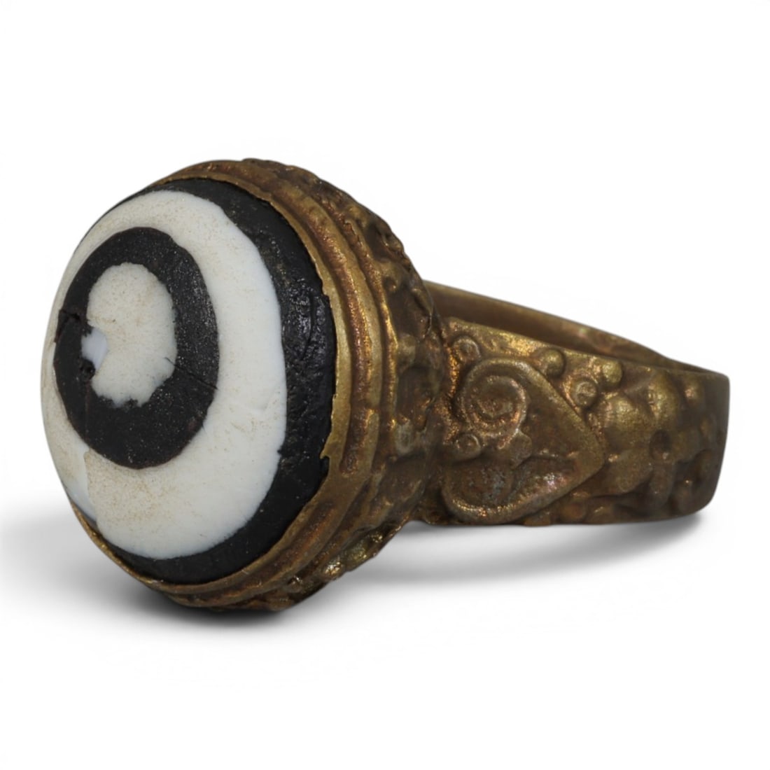 Antique Qajar Dynasty Gilt Evil Eye Ring, US Size 8.5, 10AJ: A gilt-metal ring of the Qajar period, US ring size 8.5, featuring a large domed evil-eye glass inlay with a bold concentric black-and-white design. The bezel is decorated with a textured, bubble-like
