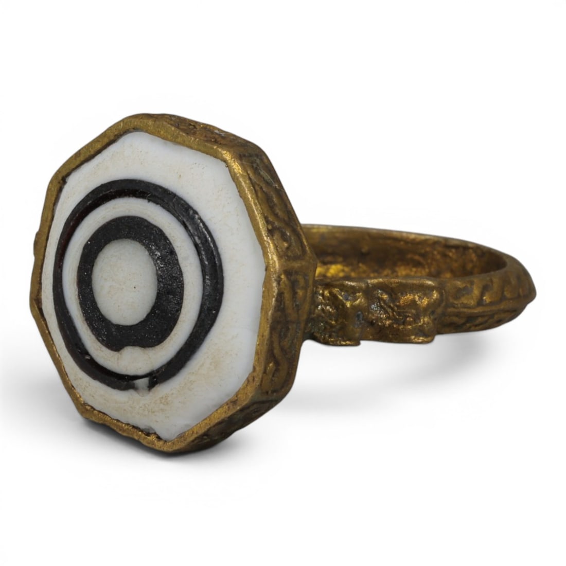 Antique Qajar Dynasty Gilt Evil Eye Ring, US Size 9, 9AJ: A gilt-metal ring of the Qajar period, US ring size 9, featuring an octagonal evil-eye glass inlay with a bold concentric black-and-white design. The bezel and band are adorned with detailed repousse 