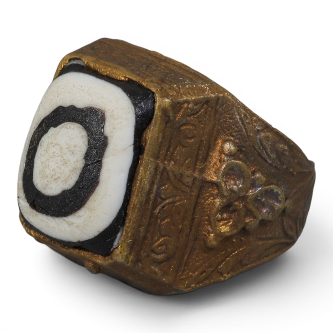 Antique Qajar Dynasty Gilt Evil Eye Ring, US Size 10, 15AJ: A gilt-metal ring of the Qajar period, US ring size 10, featuring a large square evil-eye glass inlay with a concentric black-and-white design (the glass exhibits age-related cracks). The bezel and wi