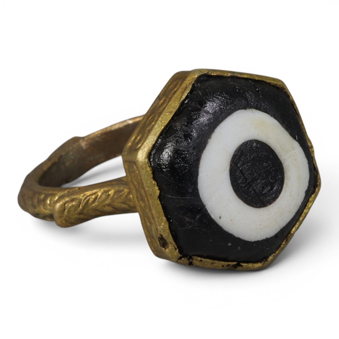 Antique Qajar Dynasty Gilt Evil Eye Ring, US Size 8, 40AJ: A gilt-metal ring of the Qajar period, US ring size 8, featuring a hexagonal evil-eye glass inlay with a bold concentric black-and-white design (the glass exhibits age-related cracks). The bezel is ad