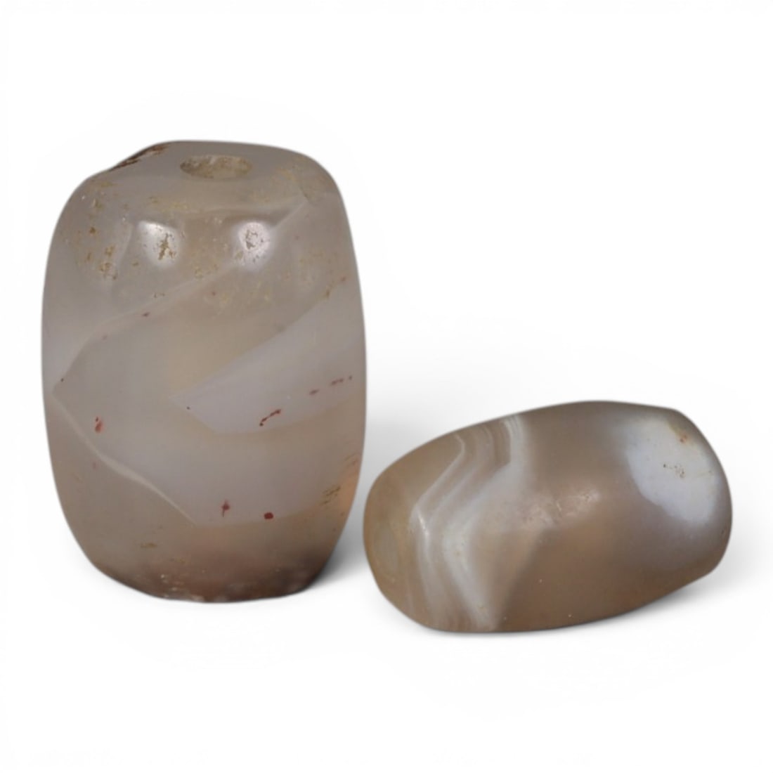A Pair of Antique Central Asian / Himalayan Banded Agate Trade Beads, 15th-19th Century, 86AJ: The pair consists of two barrel-shaped agate beads, one larger and one smaller, exhibiting natural banding in soft grey and white tones. The larger bead features subtle red mineral inclusions within i