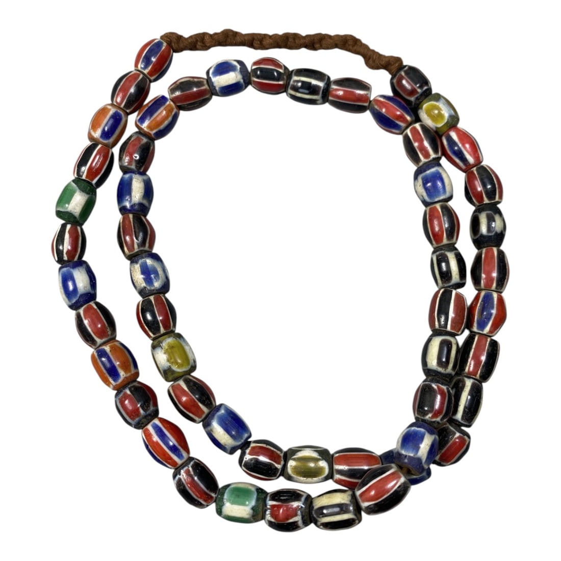 A Strand of Antique Chevron Glass Beads, Unstrung, 79AK: The strand consists of barrel-shaped chevron glass beads, primarily featuring classic red, white, blue, and black striped patterns, with a few rare green and yellow accents. The beads exhibit signs of