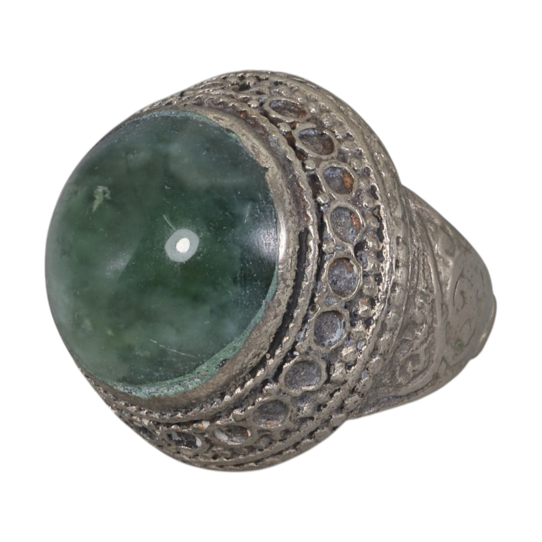 A Middle Eastern Silver Plated Green Agate Ring, Late 19th-Early 20th Century, 13AK: The ring is centered with a large round cabochon green agate stone exhibiting natural mottled green tones, set within an ornate domed bezel featuring openwork circular patterns and beaded granulation.