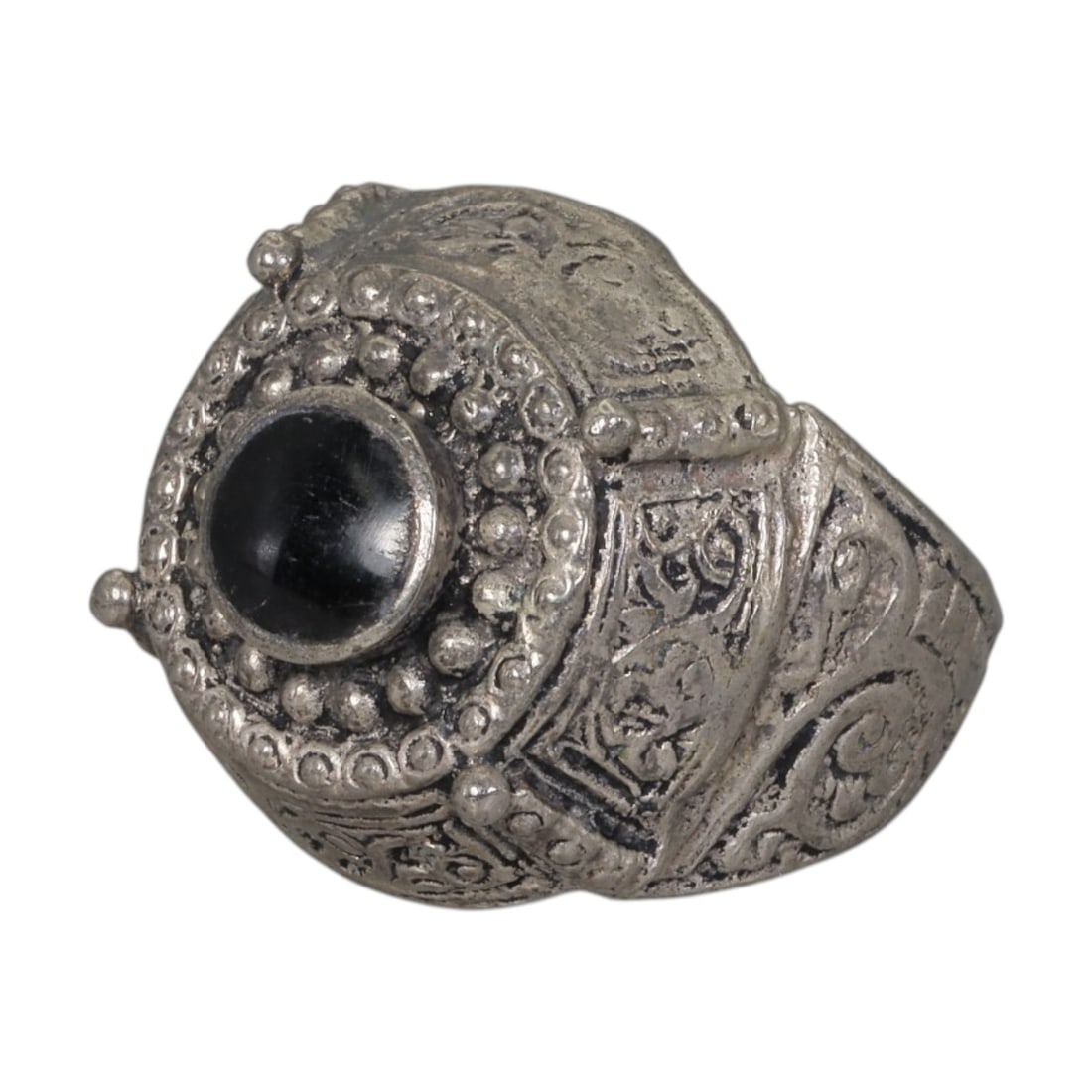 A Middle Eastern Silver Plated Onyx Ring, Late 19th-Early 20th Century, 27AK: The ring is centered with a round cabochon onyx stone set within a domed bezel framed by concentric beaded granulation. The bezel and shoulders are engraved with intricate scrolling foliate motifs, ac