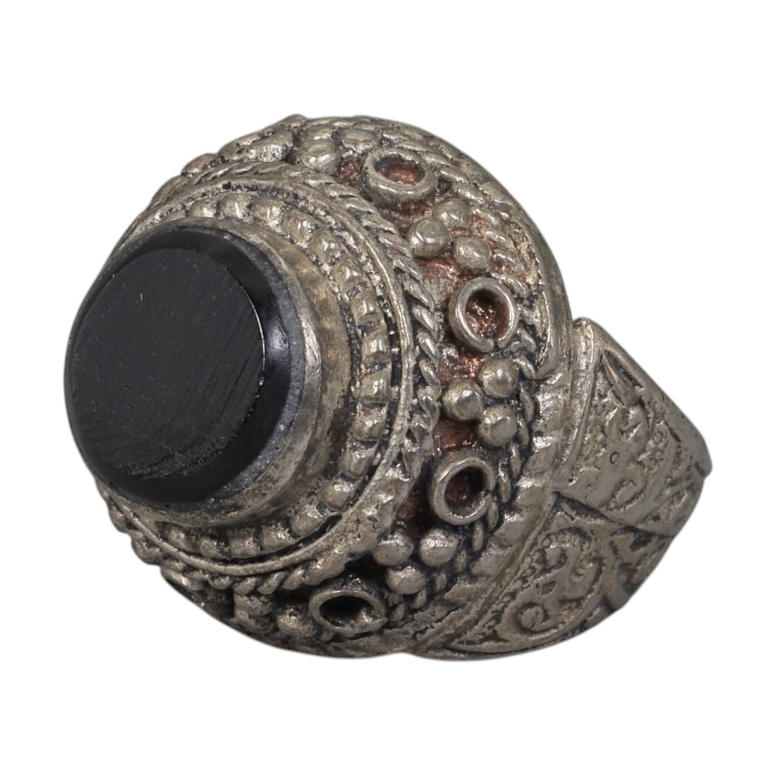 A Middle Eastern Silver Plated Onyx Ring, Late 19th-Early 20th Century, 32AK: The ring is centered with a round cabochon onyx stone set within a domed bezel decorated with beaded granulation, twisted wirework, and empty circular settings. The shoulders are engraved with scrolli