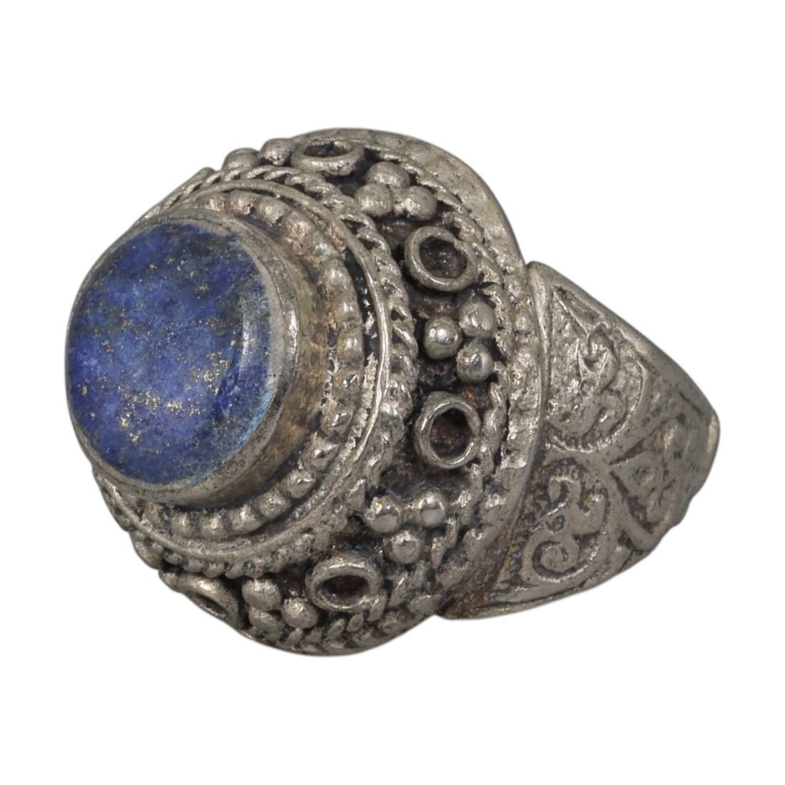 A Middle Eastern Silver Plated Lapis Lazuli Ring, Late 19th-Early 20th Century, 24AK: Set with a round cabochon lapis lazuli stone exhibiting characteristic deep blue color and natural pyrite flecks, the ring features an ornate bezel decorated with beaded granulation, twisted wirework,