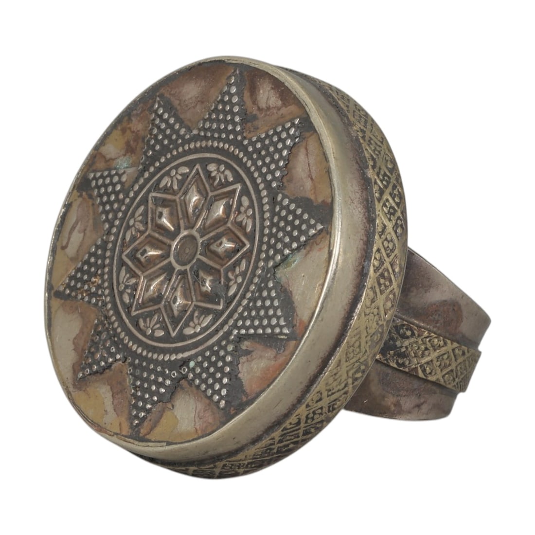 A Central Asian Silver Plated Geometric Star Motif Ring, Late 19th-Early 20th Century, 14AK: Crafted from silver plated metal with brass accents, featuring a wide, open band. The circular bezel displays a multi-layered star motif: a central eight-pointed star surrounded by small floral detail