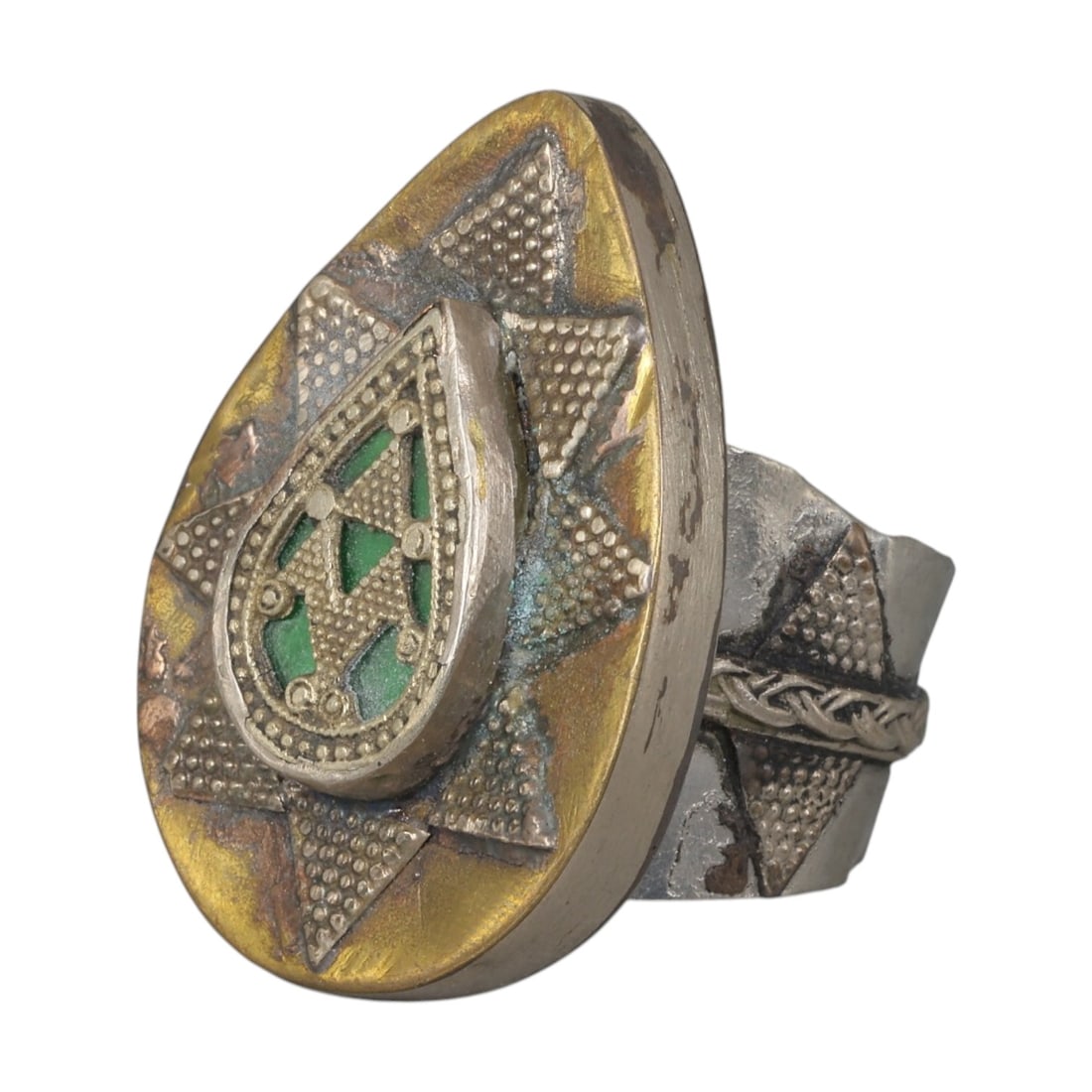A Central Asian Silver Plated Teardrop Form Ring, Late 19th-Early 20th Century, 10AK: Crafted from silver plated metal with brass accents, featuring a wide, scalloped band. The teardrop-shaped bezel displays a central raised teardrop panel with green inlaid details and geometric openwo