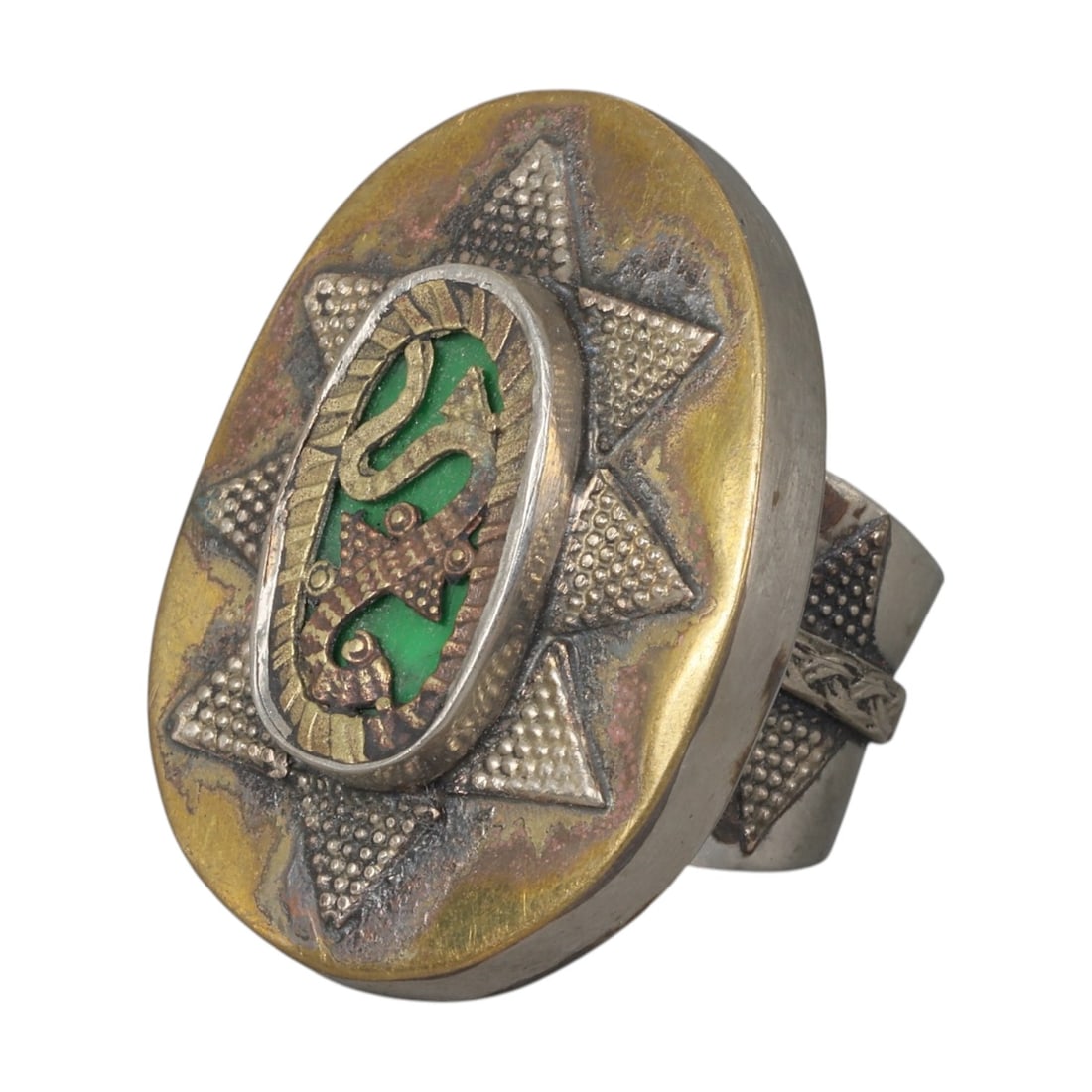 A Central Asian Silver Plated Gecko Motif Ring, Late 19th-Early 20th Century, 26AK: Crafted from silver plated metal with brass accents, featuring a wide, open band. The oval bezel displays a central inlaid panel with a green background, overlaid with a gecko motif in contrasting met