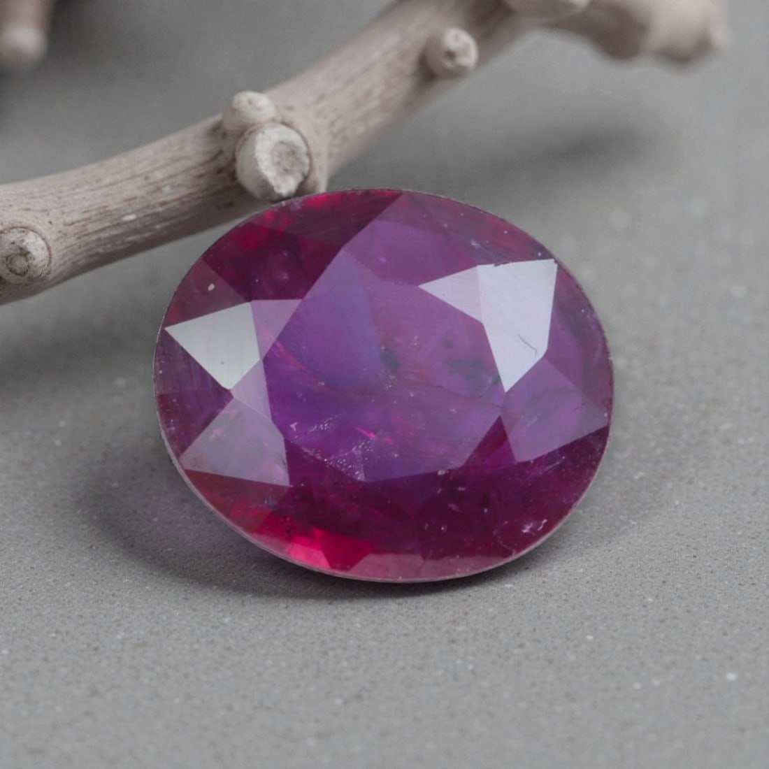 1.01 Carats Natural Pinkish Red Mozambique Ruby Oval Cut, 18AL: This oval-cut natural ruby showcases a striking pinkish-red hue, with subtle purple undertones and natural internal characteristics that add organic depth and warmth to its appearance. The faceted cut