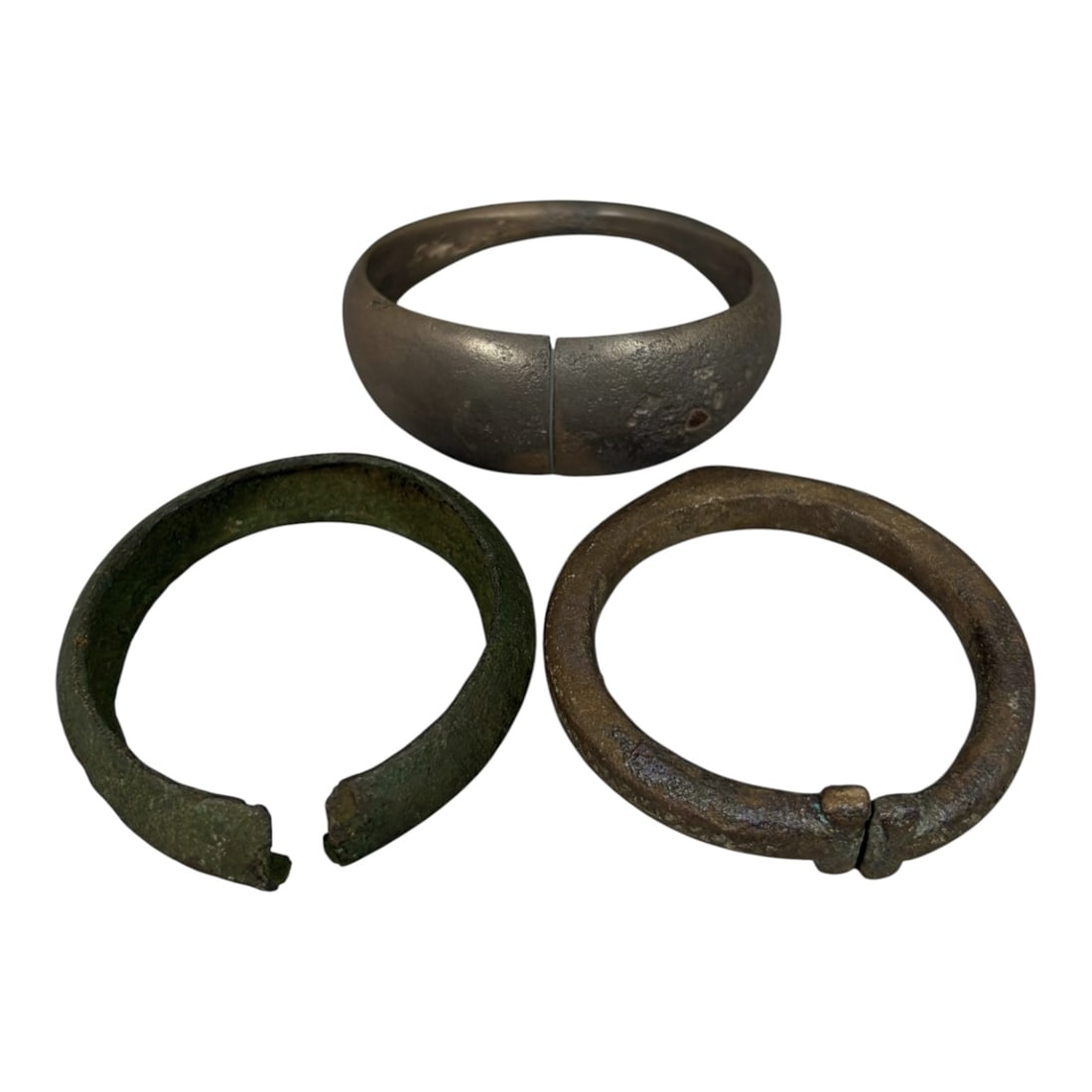 Lot of 3 Roman Bronze Bracelets, Circa 1st-4th Century CE, 88AG: A group of three bracelets crafted from bronze, representing varied Roman-period forms. The top example is a wide, penannular (open) cuff with a smooth, silvery-toned surface, showing minor surface we