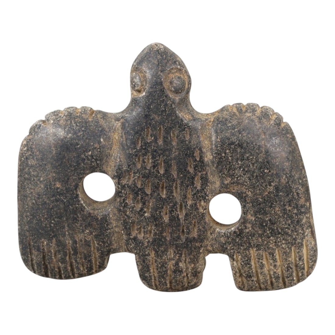 Ancient Stone Vulture Amulet - Near Eastern Bird Figure, 27AM: This vulture amulet is carved from dark speckled stone, depicting a stylized bird of prey (vulture) with outstretched wings and a compact body. The piece features incised linear and stippled detailing