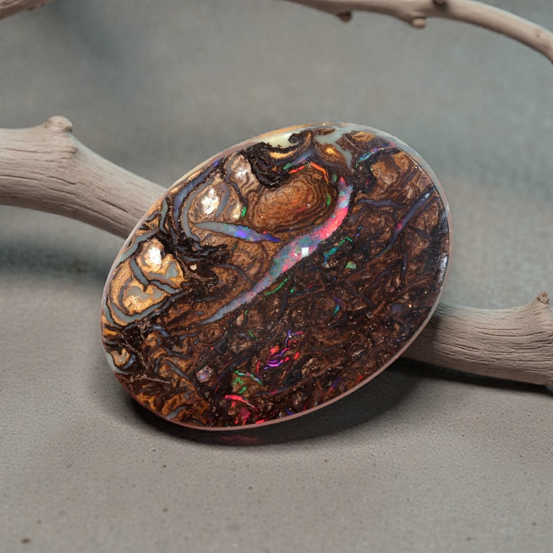 4.92 Carats Multicolor Koroit Boulder Opal - Natural Australian Stone, LZ44: This exceptional 4.92 carat Koroit boulder opal, measuring 13.9mm x 10.1mm x 3.7mm, is a masterpiece of natural artistry. Polished into a smooth oval cabochon, its face is dominated by a rich, texture