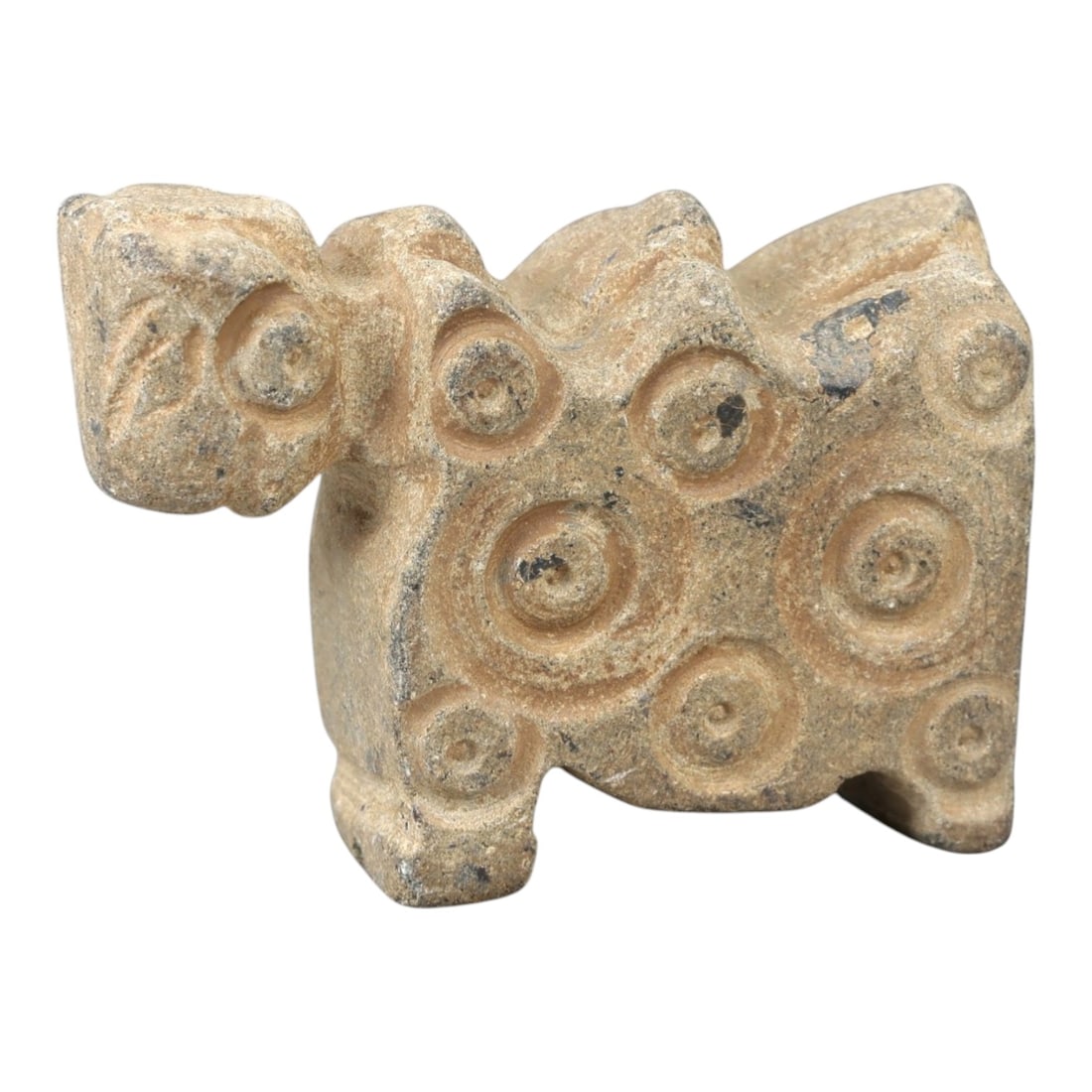 Ancient Stone Zoomorphic Figure - Near Eastern Idol, 65AM: This zoomorphic figure is carved from light stone, depicting a stylized quadrupedal animal form with a prominent head and a body adorned with concentric circular motifs in raised relief. The piece ref
