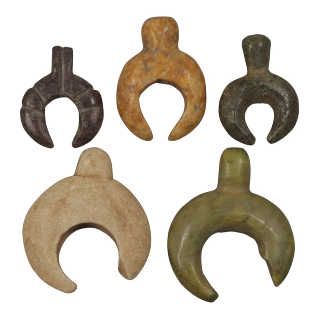 Lot of 5 Ancient Coptic Egyptian Lunar Stone Amulets, Circa Roman to Coptic Era, 100WP: Carved from various stones, including dark brown, light beige, and green varieties, the group consists of five amulets in the form of crescents or lunar pendants. Each piece features a U-shaped body w