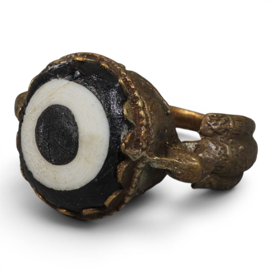 Antique Qajar Dynasty Gilt Evil Eye Ring, US Size 8, 32AJ: A gilt-metal ring of the Qajar period, US ring size 8, featuring a large domed evil-eye glass inlay with a bold concentric black-and-white design (the glass exhibits age-related cracks and patina). Th