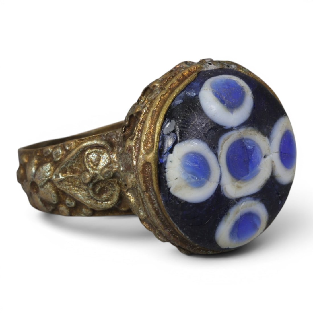 Antique Qajar Dynasty Gilt Evil Eye Ring, US Size 9, 46AJ: A gilt-metal ring of the Qajar period, US ring size 9, featuring a large domed evil-eye glass inlay with a multi-eye pattern on a deep blue background (the glass exhibits age-related cracks). The beze