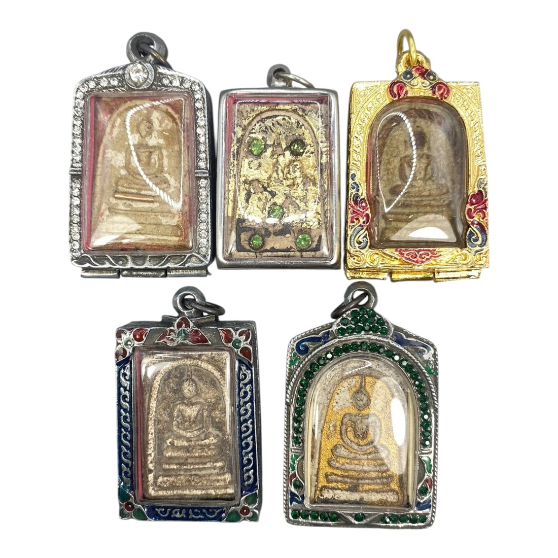 A Lot of 5 Vintage Thai Buddhist Amulets with Enamel and Jewel Accents, 13WT: A curated lot of five vintage Thai Buddhist amulets, each encased in ornate metal frames with enamel detailing and jewel accents. The amulets depict traditional seated Buddha iconography, with varying