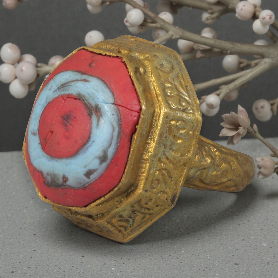 Antique Qajar Dynasty Gilt Evil Eye Ring, US Size 8, 7AJ: A gilt-metal ring of the Qajar period, US ring size 8, featuring a hexagonal evil-eye glass inlay with a vibrant red and light blue concentric design. The bezel and band are adorned with detailed repo