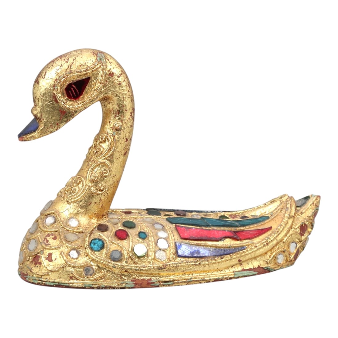 A Southeast Asian Gilt Wood Swan Figure, 20th Century, 51FK: Carved from wood and modeled as a stylized swan shown resting with an arched neck and forward-facing head, the figure is decorated overall with gilt surface treatment and inset colored glass elements.