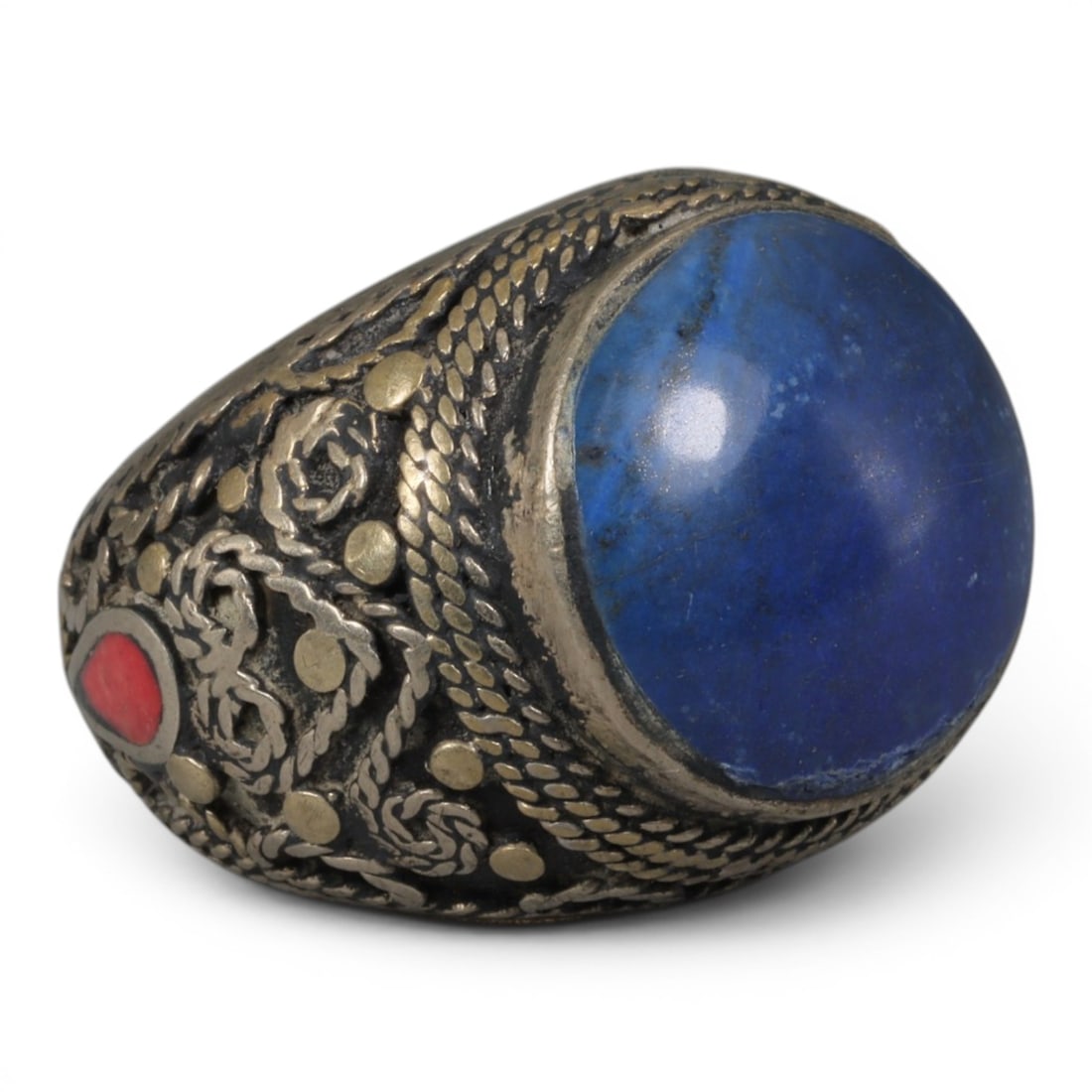 Antique Central Asian Silver and Lapis Lazuli Tribal Ring, 19th-Early 20th Century, 56AJ: The ring is set with a large, smooth cabochon lapis lazuli stone, displaying natural tonal variations within its deep blue matrix. The silver mount is decorated with pseudo-filigree wirework, applied 