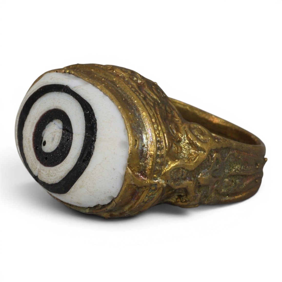 Antique Qajar Dynasty Gilt Evil Eye Ring, US Size 8, 23AJ: A gilt-metal ring of the Qajar period, US ring size 8, featuring a large domed evil-eye glass inlay with a bold concentric black-and-white design (the glass exhibits age-related cracks). The domed bez