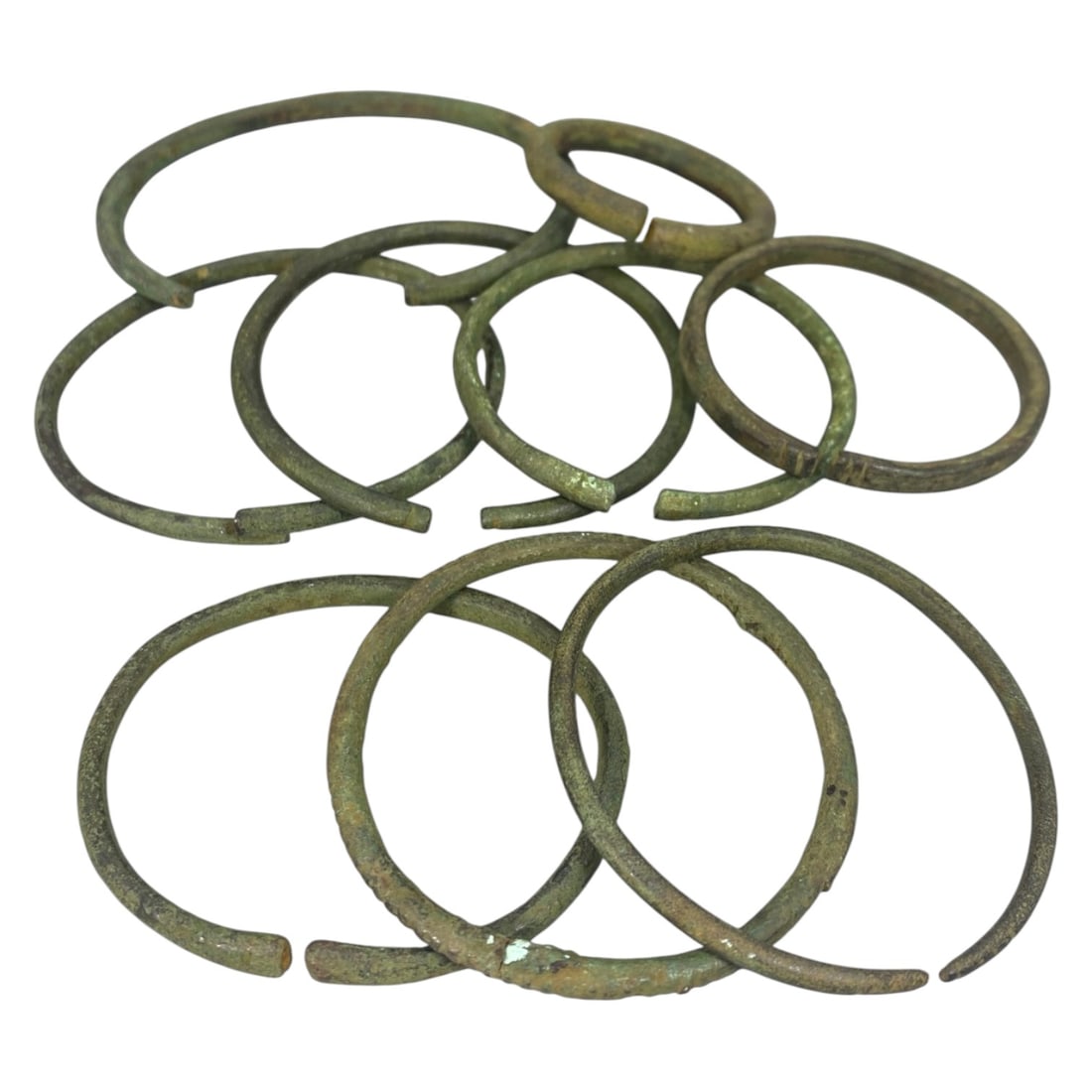 Lot of 9 Roman Bronze Bracelets, Circa 1st-4th Century CE, 95AC: Each bracelet is formed from a single length of bronze, hammered into a circular band with open, overlapping terminals. The metal exhibits a consistent green patina, with some examples showing surface