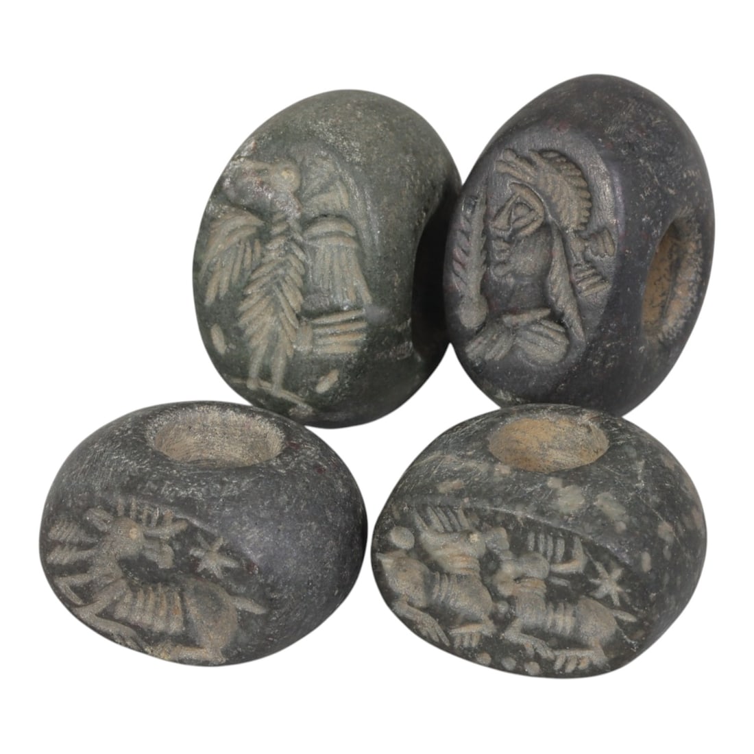 Lot of 4 Ancient Sasanian Stone Stamp Seals, Circa 3rd-7th Century CE, 72WP: A collection of four Sasanian period stamp seals, carved from dark grey/black stone, each featuring a central drilled hole for suspension. The seals display characteristic Sasanian iconography: includ