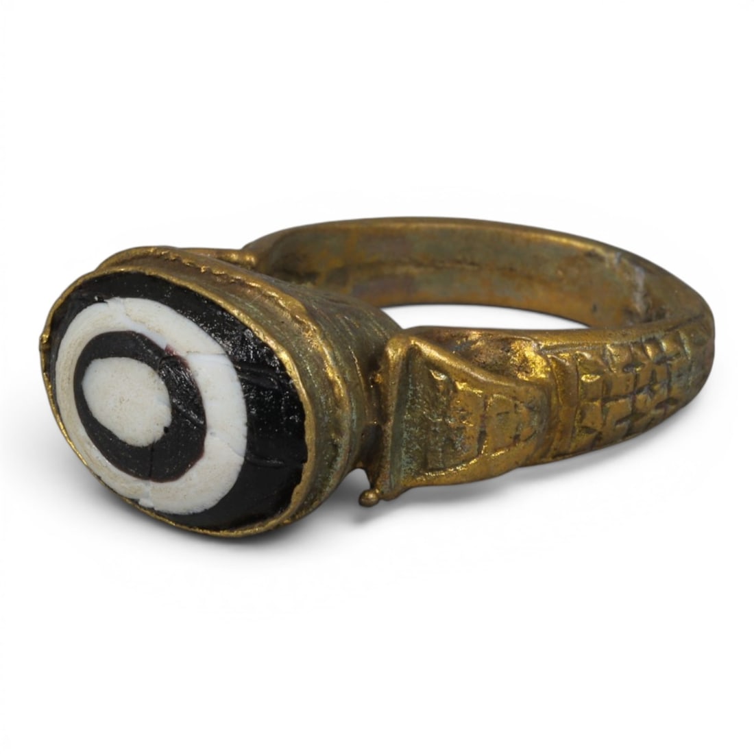 Antique Qajar Dynasty Gilt Evil Eye Ring, US Size 9, 12AJ: A gilt-metal ring of the Qajar period, US ring size 9, featuring an oval evil-eye glass inlay with a bold concentric black-and-white design (the glass exhibits age-related cracks). The domed bezel and