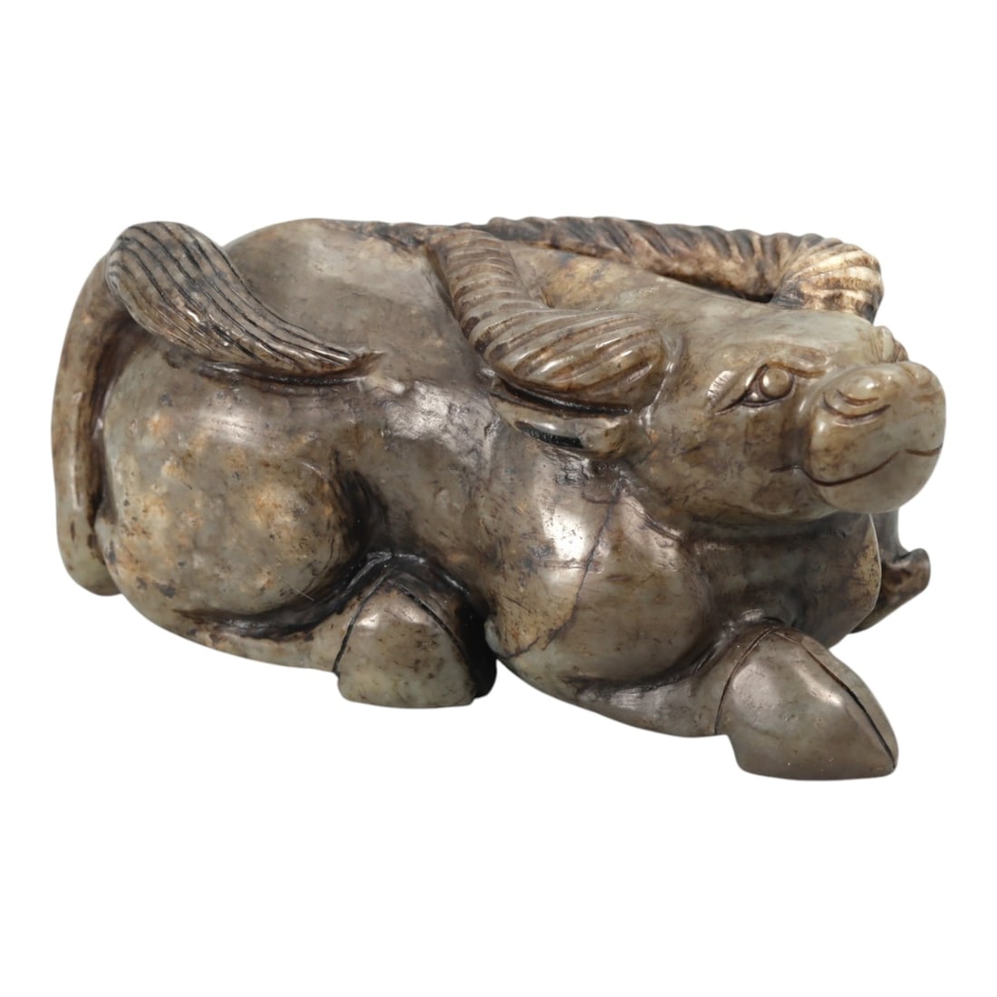 A Chinese Jade Buffalo Sculpture, 20th Century, 34YA: Carved from mottled grey-green jade with areas of brown and dark mineral inclusions, the sculpture represents a recumbent water buffalo modeled fully in the round. The animal is shown resting with its