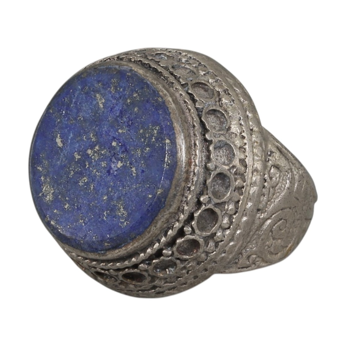 A Middle Eastern Silver Plated Lapis Lazuli Ring, Late 19th-Early 20th Century, 35AK: The ring is centered with a large round cabochon lapis lazuli stone exhibiting deep blue color with natural pyrite flecks, set within a wide domed bezel decorated with openwork circular patterns and t