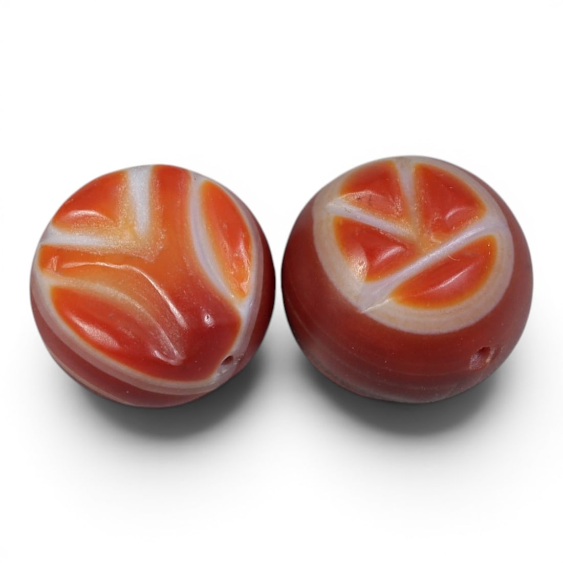 A Pair of Antique Himalayan Banded Carnelian Beads, 76AJ: The pair consists of two round carnelian beads, each displaying unique natural banding patterns. The left bead features flowing, abstract orange and white striations, while the right bead shows a fan-