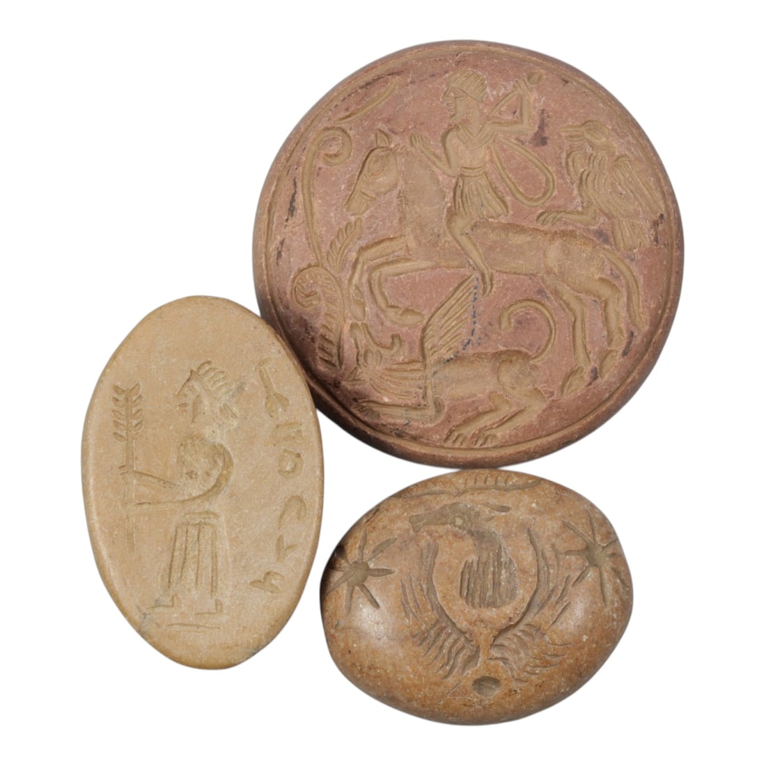 Lot of 3 Ancient Near Eastern Stone Plaque and Stamps, 97WM: A collection of three ancient Near Eastern stone plaques and stamps, carved from light and reddish-brown stone. The set includes: a round plaque engraved with a mounted figure, winged beast, and bird 