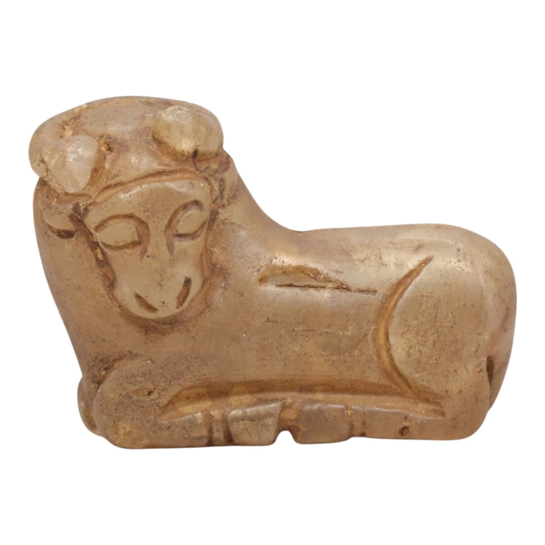 Ancient Rock Crystal Bovid - Near Eastern Amulet Figurine, 100ZP: Carved from translucent pale rock crystal, this reclining bovid figurine features stylized curved horns, closed incised eyes, and simplified facial features. The compact, rounded body is defined by su